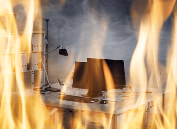 A small business office with two desks with computer workstations on fire